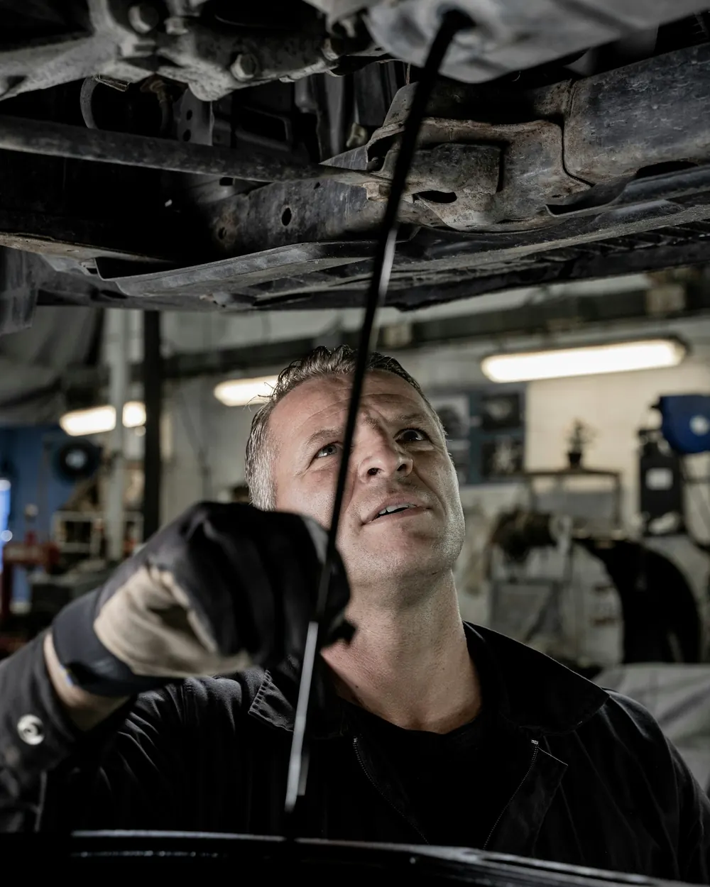 Technician working underneath a car on a lift